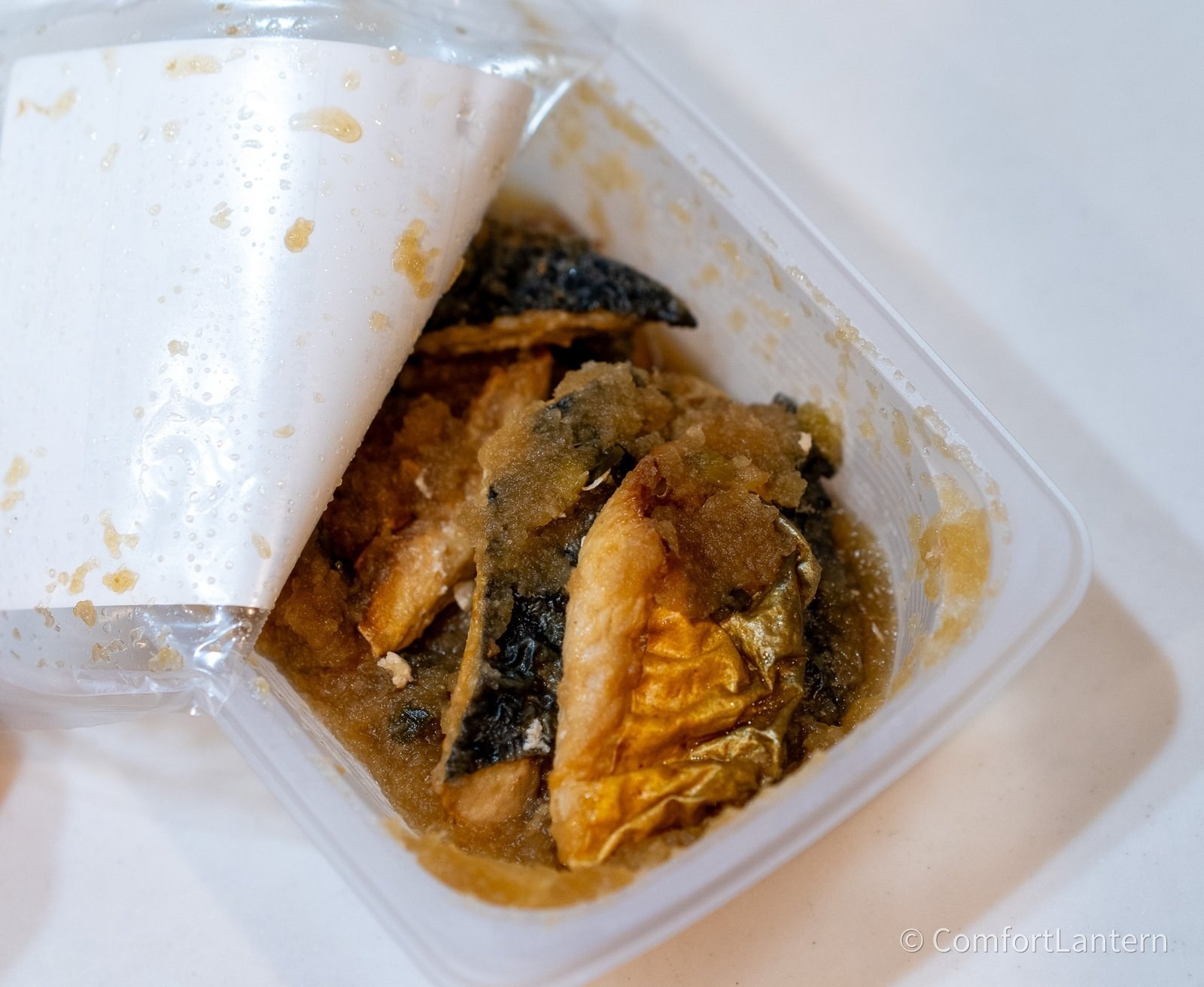容器を開けたさばのみぞれ煮。皮付きの鯖に大根おろしがかかっている