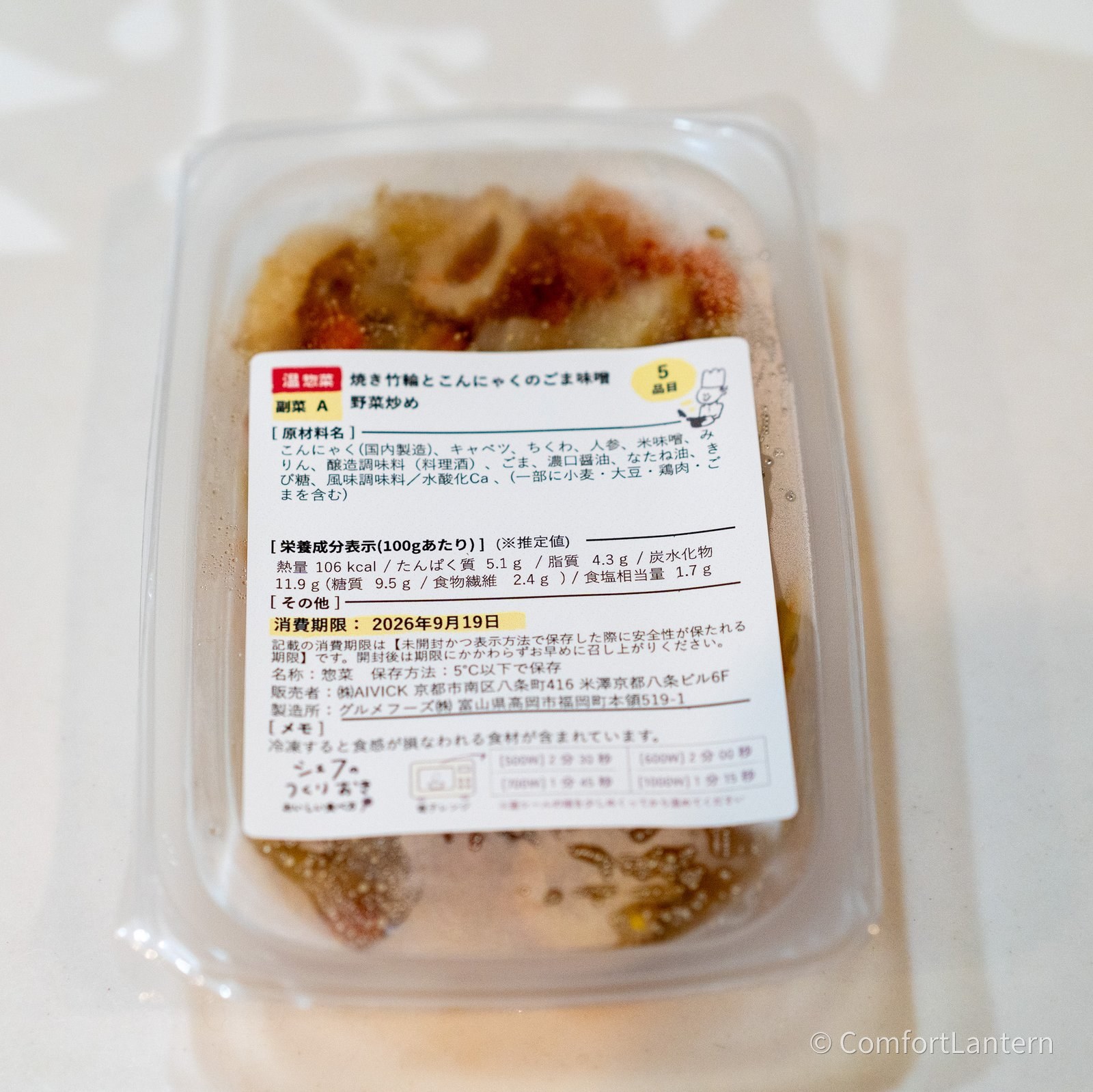 焼き竹輪とこんにゃくのごま味噌野菜炒めの容器に貼られたラベル。原材料にこんにゃく(国内製造)、キャベツ、ちくわ、人参などが並んでいる