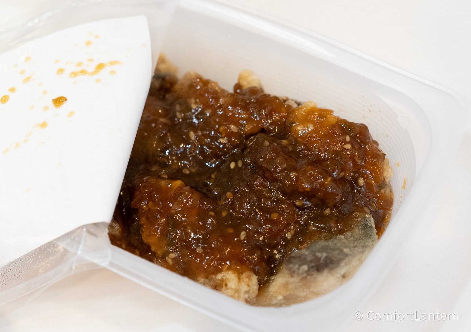 容器を開けたアジの唐揚げ 香味だれかけ。唐揚げに濃い色のたれが固まってかかっている